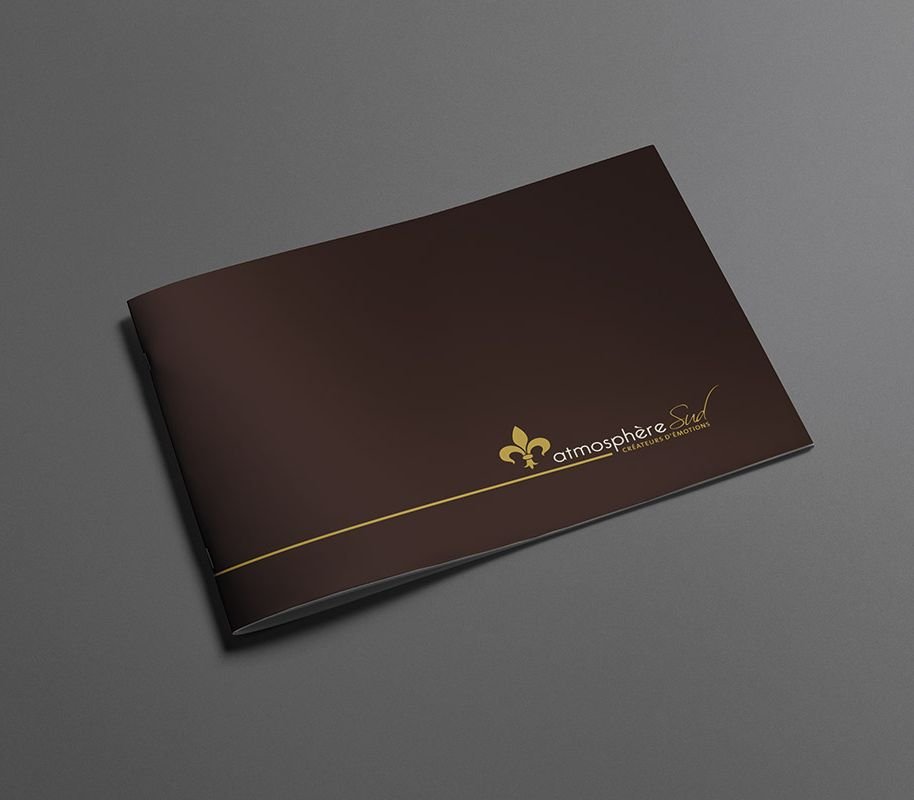 Brochure à couverture souple sombre marquée à l'or, posée à plat